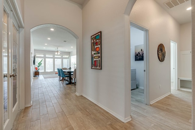 hall with light hardwood / wood-style floors and a high ceiling