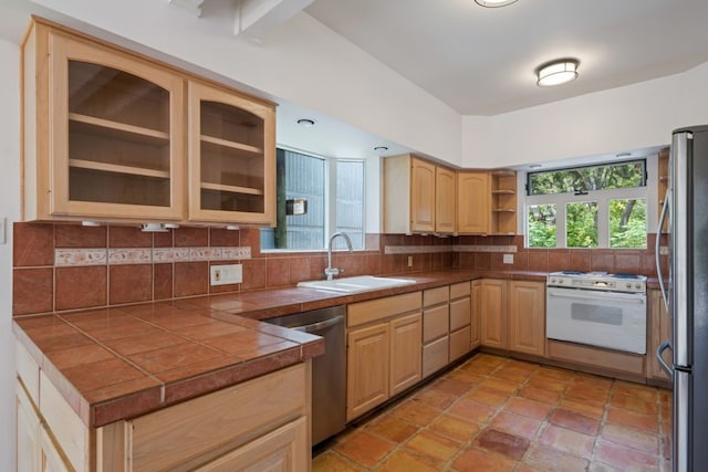 kitchen with tile counters, sink, stainless steel appliances, light brown cabinets, and tasteful backsplash