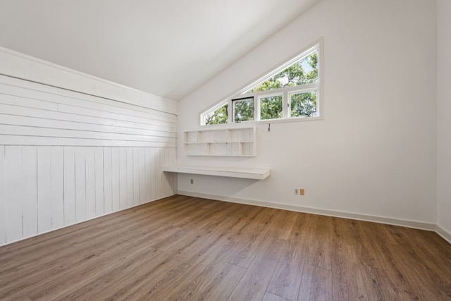 additional living space featuring wood walls, wood-type flooring, and vaulted ceiling