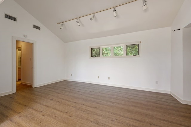 spare room with hardwood / wood-style flooring, rail lighting, and high vaulted ceiling