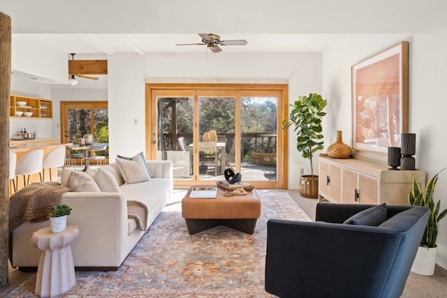 living room with carpet flooring, ceiling fan, and beamed ceiling