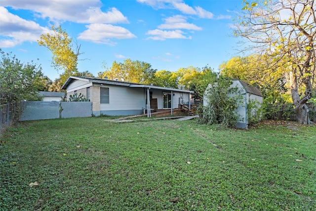 back of house with a shed and a lawn