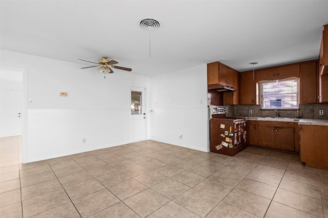 8507 Contour Dr, Austin, TX 78757 - kitchen with under cabinet range hood, a ceiling fan, light tile patterned flooring, decorative backsplash, and light countertops