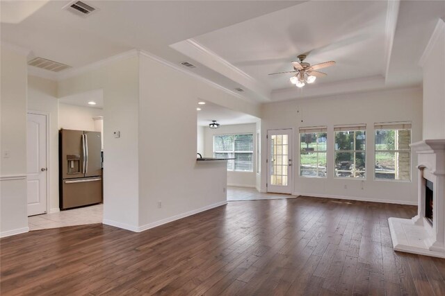 3704 Bunyan Cir, Lago Vista, TX 78645 - unfurnished living room featuring a raised ceiling, wood-type flooring, ornamental molding, ceiling fan, and a lit fireplace
