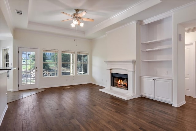 3704 Bunyan Cir, Lago Vista, TX 78645 - unfurnished living room featuring dark wood-type flooring, ceiling fan, a tray ceiling, ornamental molding, and a lit fireplace