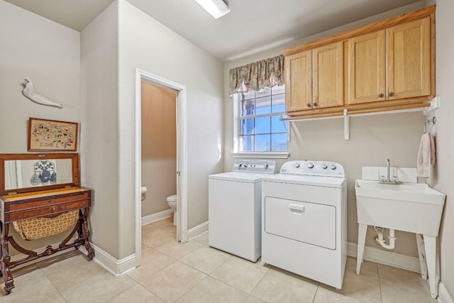 laundry room with cabinets, light tile patterned floors, and washing machine and clothes dryer