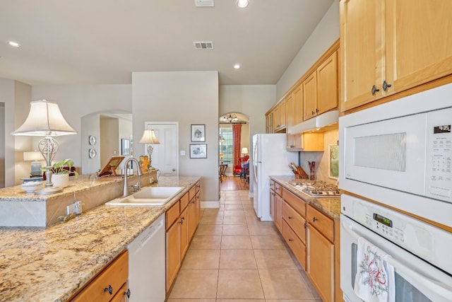 kitchen featuring light brown cabinets, white appliances, sink, light tile patterned flooring, and light stone counters