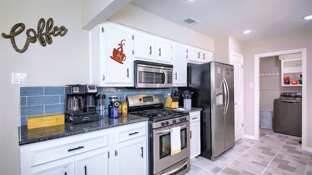 kitchen featuring white cabinetry, stainless steel appliances, backsplash, washer / clothes dryer, and dark stone counters