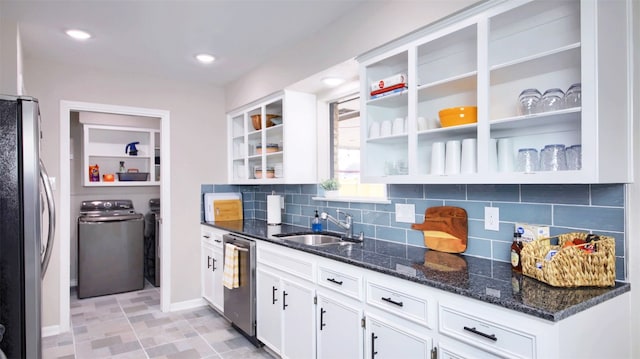 kitchen with white cabinets, sink, washer and dryer, dark stone countertops, and stainless steel appliances