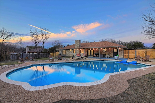 pool at dusk featuring a patio