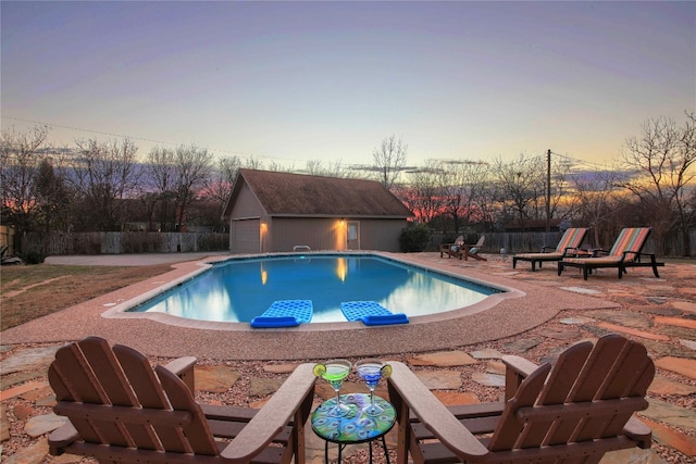 pool at dusk with a patio and an outdoor structure