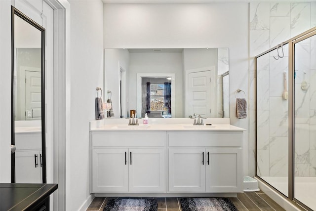 bathroom featuring double vanity, a shower stall, wood tiled floor, and a sink