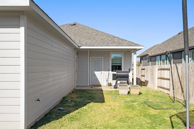 back of property featuring a lawn, roof with shingles, and fence