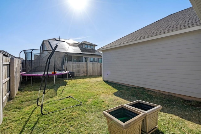 view of yard with a trampoline and a fenced backyard