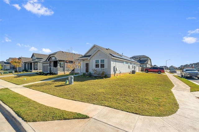 view of front of home with solar panels, a residential view, board and batten siding, and a front yard