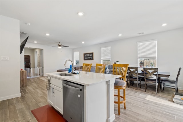 kitchen with white cabinetry, sink, stainless steel dishwasher, a center island with sink, and light wood-type flooring