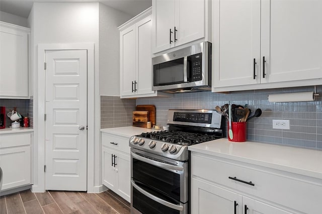 kitchen featuring wood finished floors, light countertops, white cabinets, appliances with stainless steel finishes, and tasteful backsplash