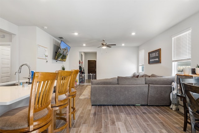 living room with ceiling fan, sink, and dark wood-type flooring