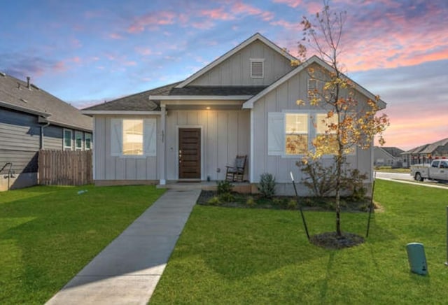 view of front of home featuring board and batten siding, a yard, and fence