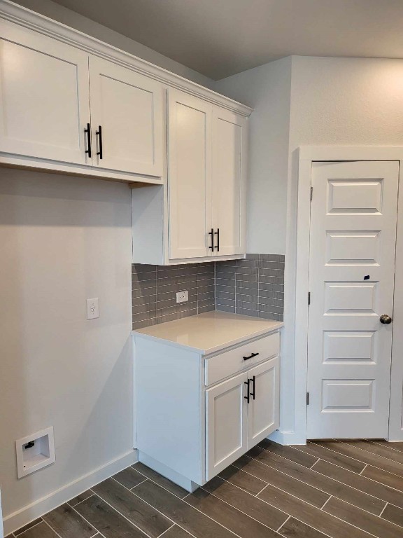 kitchen featuring wood finish floors, tasteful backsplash, white cabinets, light countertops, and baseboards