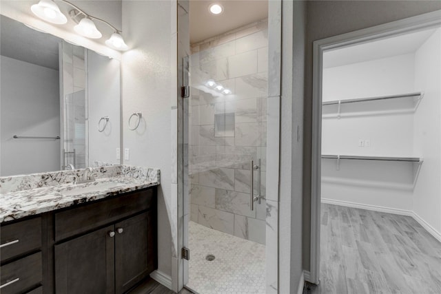 bathroom with hardwood / wood-style flooring, vanity, and a shower with door