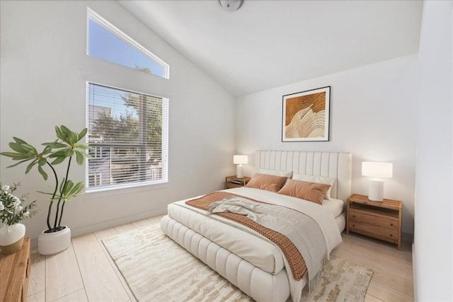 bedroom with multiple windows, light hardwood / wood-style flooring, and lofted ceiling