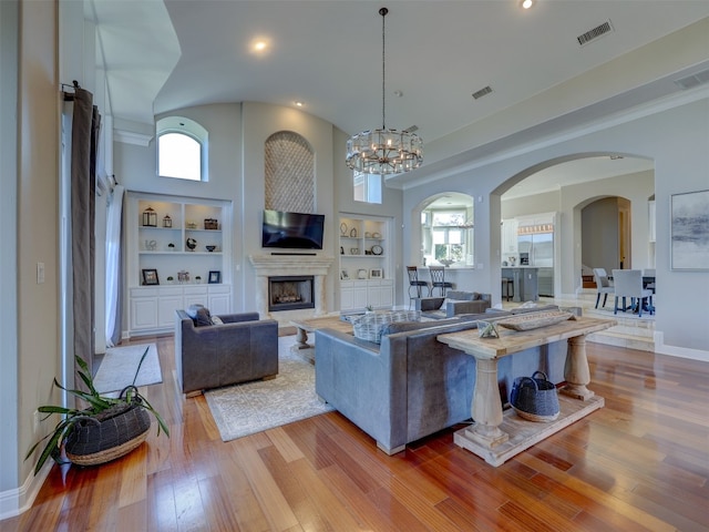 living room with built in shelves, light hardwood / wood-style floors, and a wealth of natural light