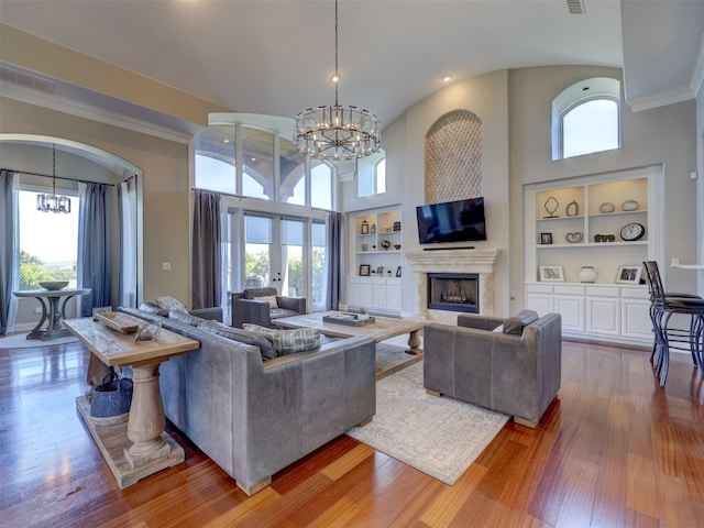 living room featuring built in shelves, a healthy amount of sunlight, and a high ceiling