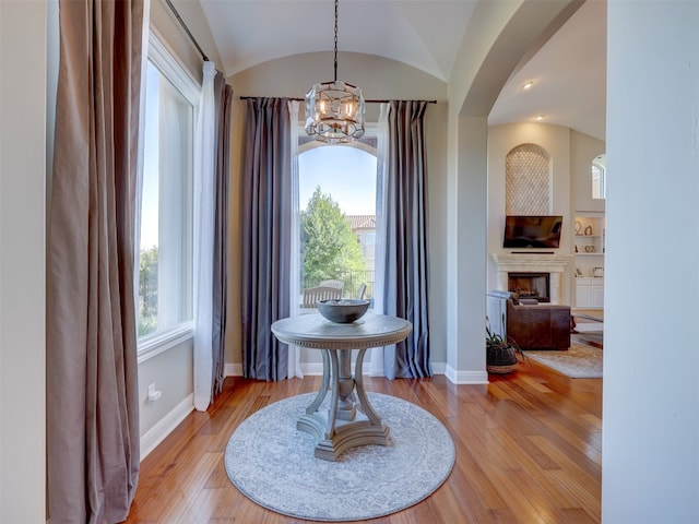 foyer entrance with a notable chandelier, light wood-type flooring, a wealth of natural light, and vaulted ceiling