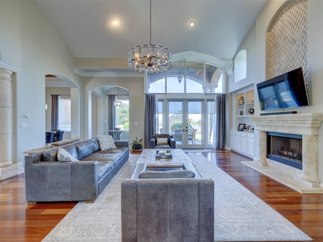 living room featuring dark hardwood / wood-style flooring, a premium fireplace, high vaulted ceiling, and a chandelier