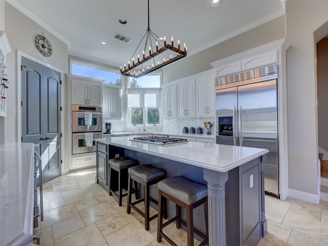 kitchen featuring backsplash, white cabinetry, a kitchen island, and appliances with stainless steel finishes