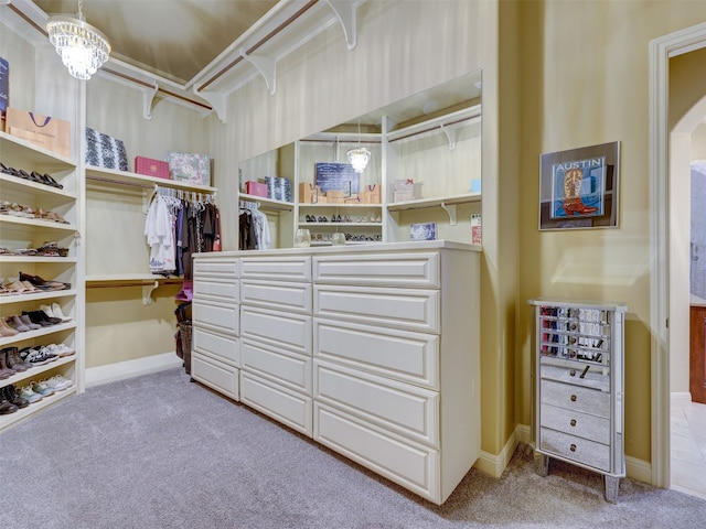 walk in closet with light colored carpet and a notable chandelier