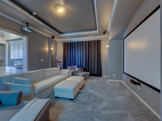 home theater with light colored carpet, a raised ceiling, and ornamental molding