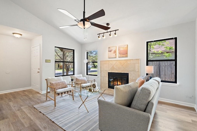 living room with ceiling fan, a fireplace, light hardwood / wood-style floors, and vaulted ceiling