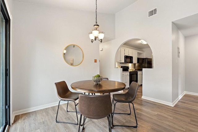 dining room featuring high vaulted ceiling and light hardwood / wood-style floors