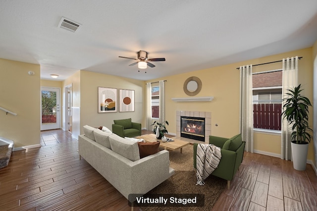 living room with a fireplace, wood-type flooring, and ceiling fan