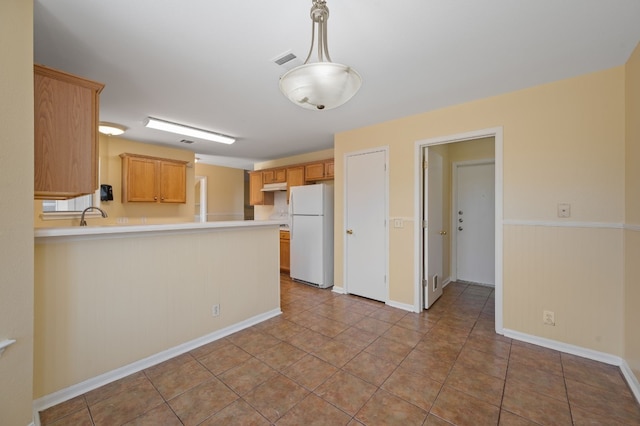 kitchen with light brown cabinets, sink, kitchen peninsula, white fridge, and light tile patterned floors