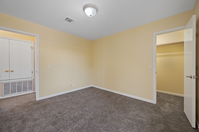 unfurnished bedroom featuring dark colored carpet, a spacious closet, and a closet