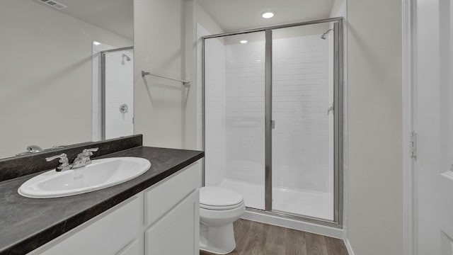 bathroom with vanity, hardwood / wood-style flooring, a shower with shower door, and toilet