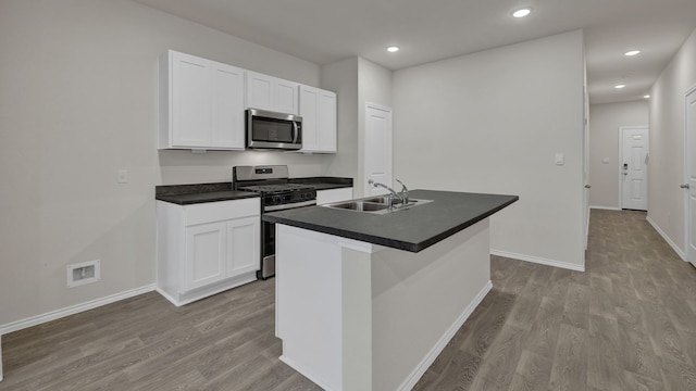 kitchen featuring sink, appliances with stainless steel finishes, white cabinetry, an island with sink, and light wood-type flooring