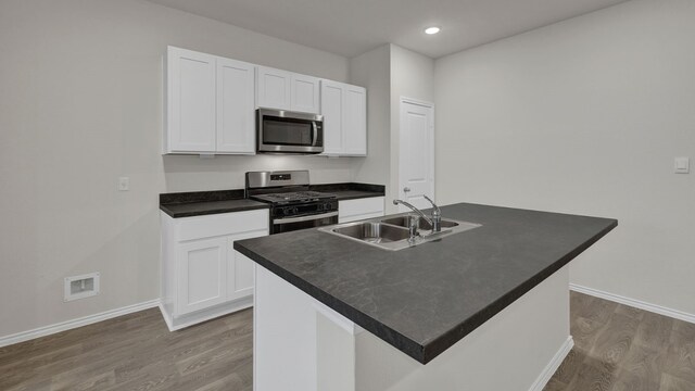 kitchen featuring an island with sink, appliances with stainless steel finishes, sink, and white cabinets