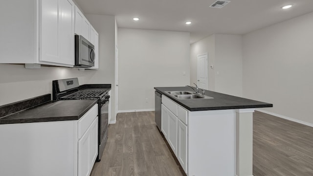 kitchen featuring sink, appliances with stainless steel finishes, white cabinetry, light hardwood / wood-style floors, and an island with sink