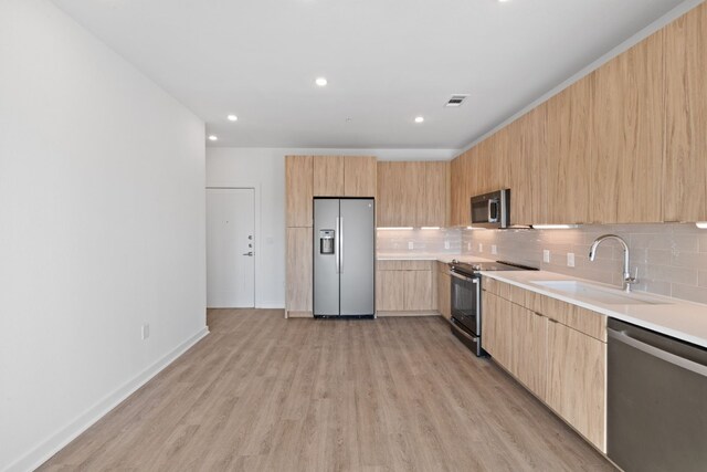 kitchen featuring appliances with stainless steel finishes, light hardwood / wood-style floors, light brown cabinetry, and sink