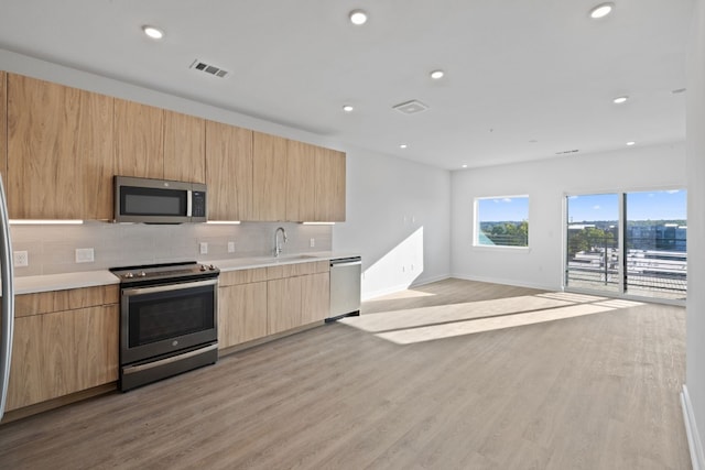 kitchen featuring light brown cabinets, sink, light hardwood / wood-style flooring, decorative backsplash, and appliances with stainless steel finishes