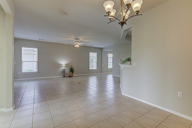 tiled spare room with ceiling fan with notable chandelier