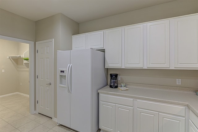 kitchen featuring white cabinetry, white fridge with ice dispenser, and light tile patterned flooring