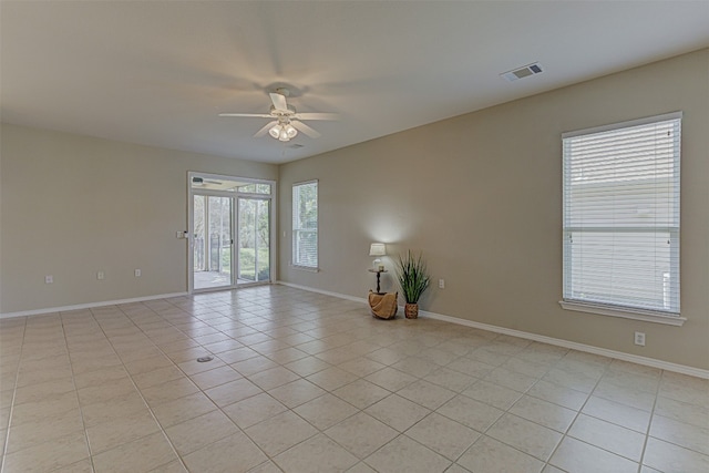 empty room featuring ceiling fan, a healthy amount of sunlight, and light tile patterned flooring