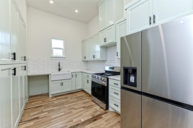 kitchen featuring white cabinets, sink, stainless steel appliances, and light hardwood / wood-style flooring