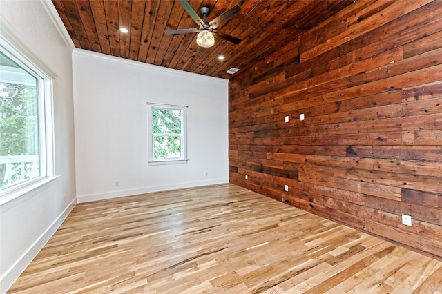 empty room featuring wood walls, light hardwood / wood-style floors, wooden ceiling, and crown molding