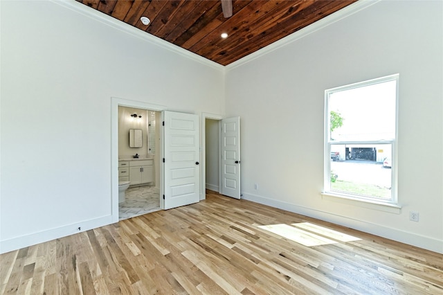 unfurnished bedroom featuring light wood-type flooring, wooden ceiling, connected bathroom, and a towering ceiling